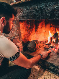 Full length of man sitting by fire