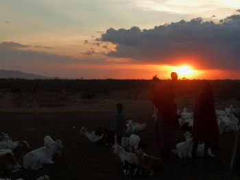 Silhouette of people on landscape at sunset