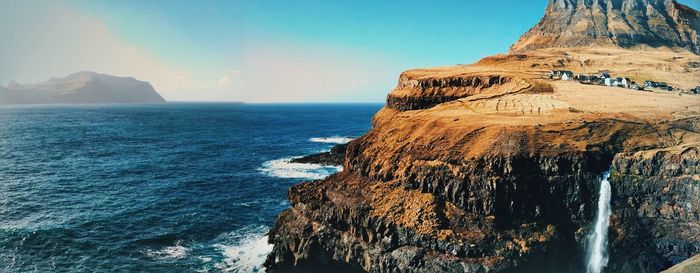 Scenic view of cliff by sea against sky