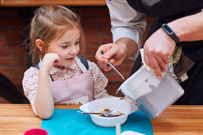 Midsection of man serving food to girl on table