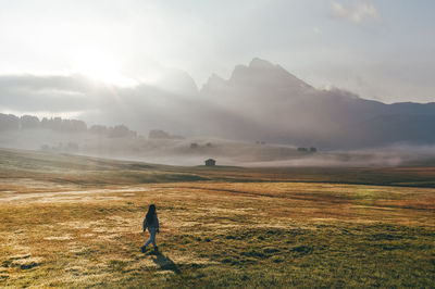 Woman walking on field against sky