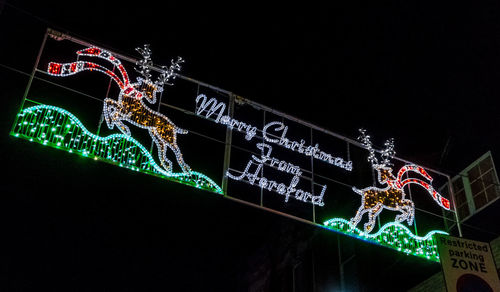 Low angle view of illuminated sign against clear sky at night