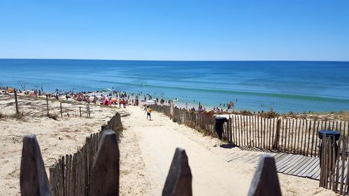 Panoramic view of people on beach against clear blue sky