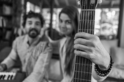 Portrait of woman holding guitar by man playing harmonium