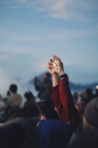 Close-up of man photographing woman using smart phone against sky