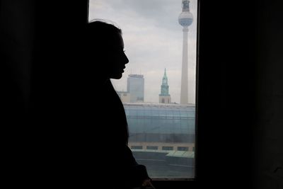 Silhouette woman standing by window