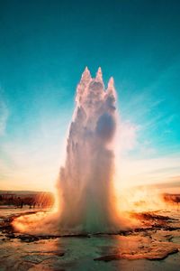 Scenic view of geyser erupting against sky