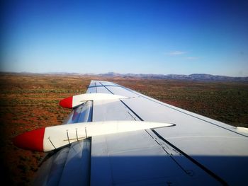 Close-up of airplane wing against clear blue sky