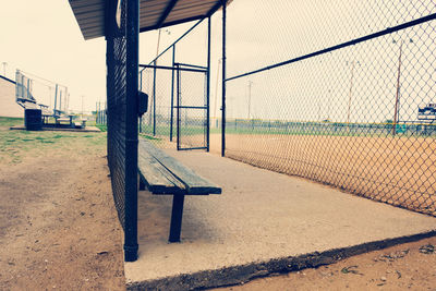 Empty bench in park against sky