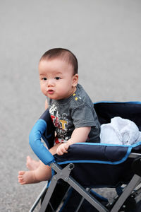 Cute baby sitting in baby stroller outdoors