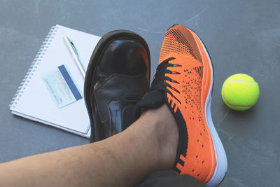 Low section of man by tennis ball and book