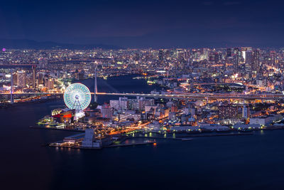 Illuminated ferris wheel and buildings in city at night