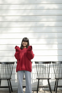 Portrait of young woman standing against railing