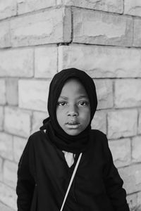 Portrait of teenage boy standing against brick wall