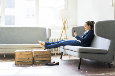 Businesswoman sitting on couch using cell phone