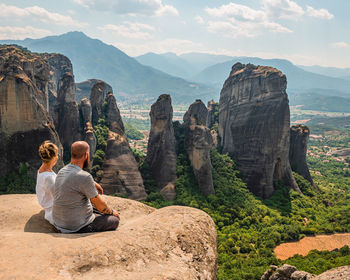 Couple sitting facing with panorama at meteora in greece