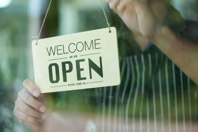 Midsection of man holding information sign seen through glass window