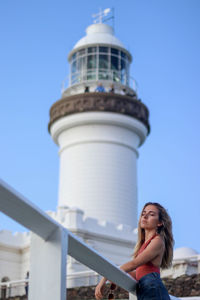 Portrait of young woman leaning next to the lighthouse of byron bay, australia