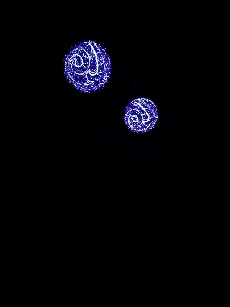 LOW ANGLE VIEW OF ILLUMINATED LIGHTS HANGING AGAINST BLACK BACKGROUND