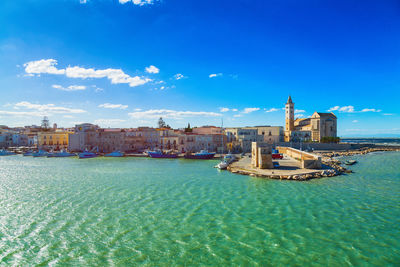 View of buildings at waterfront against blue sky