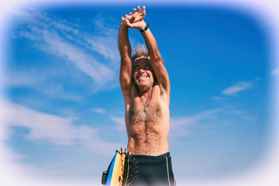 Low angle view of man with arms raised against sky