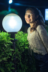 Young woman smiling while standing at night