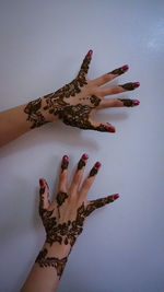 Cropped image of woman with henna tattoo against white wall