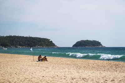 People at beach against sky