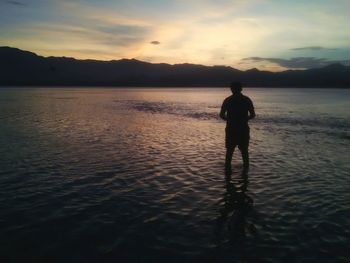 Silhouette of man standing on mountain at sunset