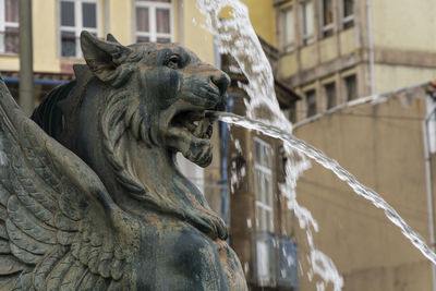 Close-up of statue by fountain against building