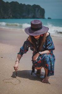Woman carving on sand at beach