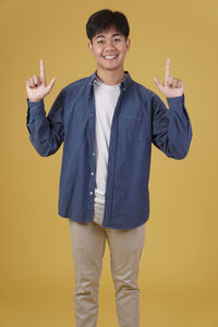 Portrait of smiling boy standing against yellow background