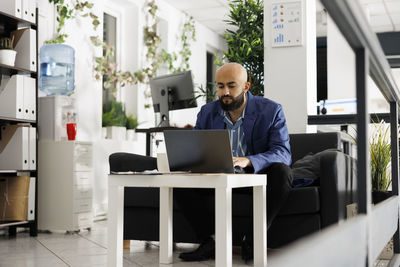 Side view of young man using digital tablet in office