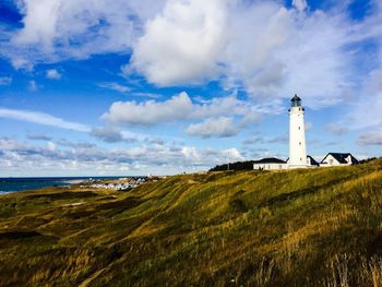 Lighthouse by sea against sky