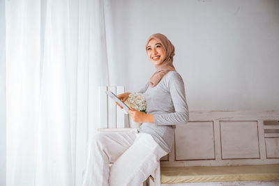 Portrait of young woman sitting on bed at home