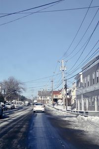 Cars on road in city against sky during winter