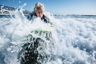 Senior man surfing in sea