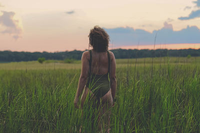 Rear view of shirtless man standing on field against sky