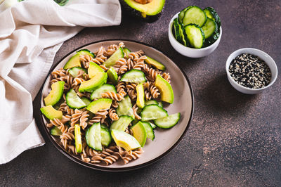 Gluten free buckwheat pasta, cucumber and avocado on a plate on the table