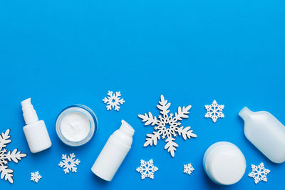 High angle view of pills spilling from bottle against blue background