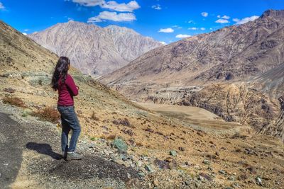 Rear view of woman standing on mountain against sky