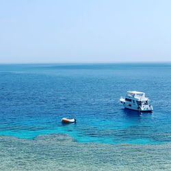 Boat sailing in sea against clear sky