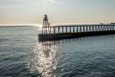 Pier over sea against sky during sunset