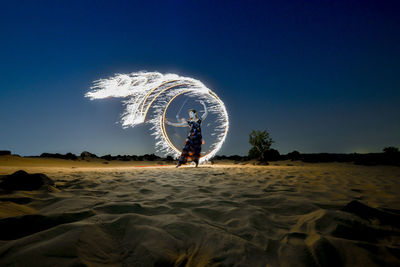 Ferris wheel on beach against sky at night