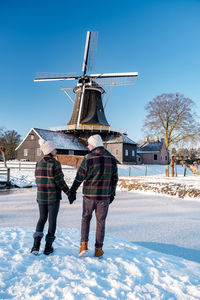 Traditional windmill on snow against sky