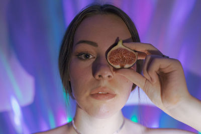 Close-up portrait of young woman holding fig