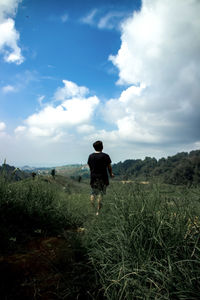 Rear view of man standing on field against sky