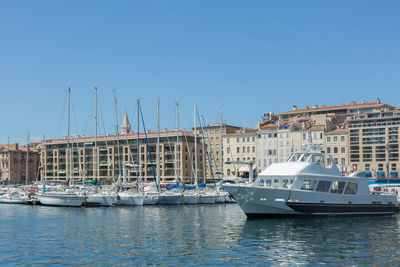 Sailboats moored at harbor against clear blue sky