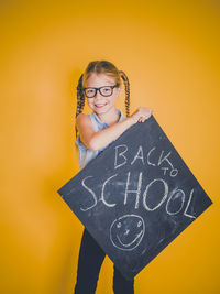 Portrait of smiling girl holding yellow background