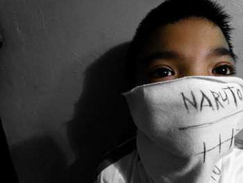 Close-up portrait of boy with mask against wall